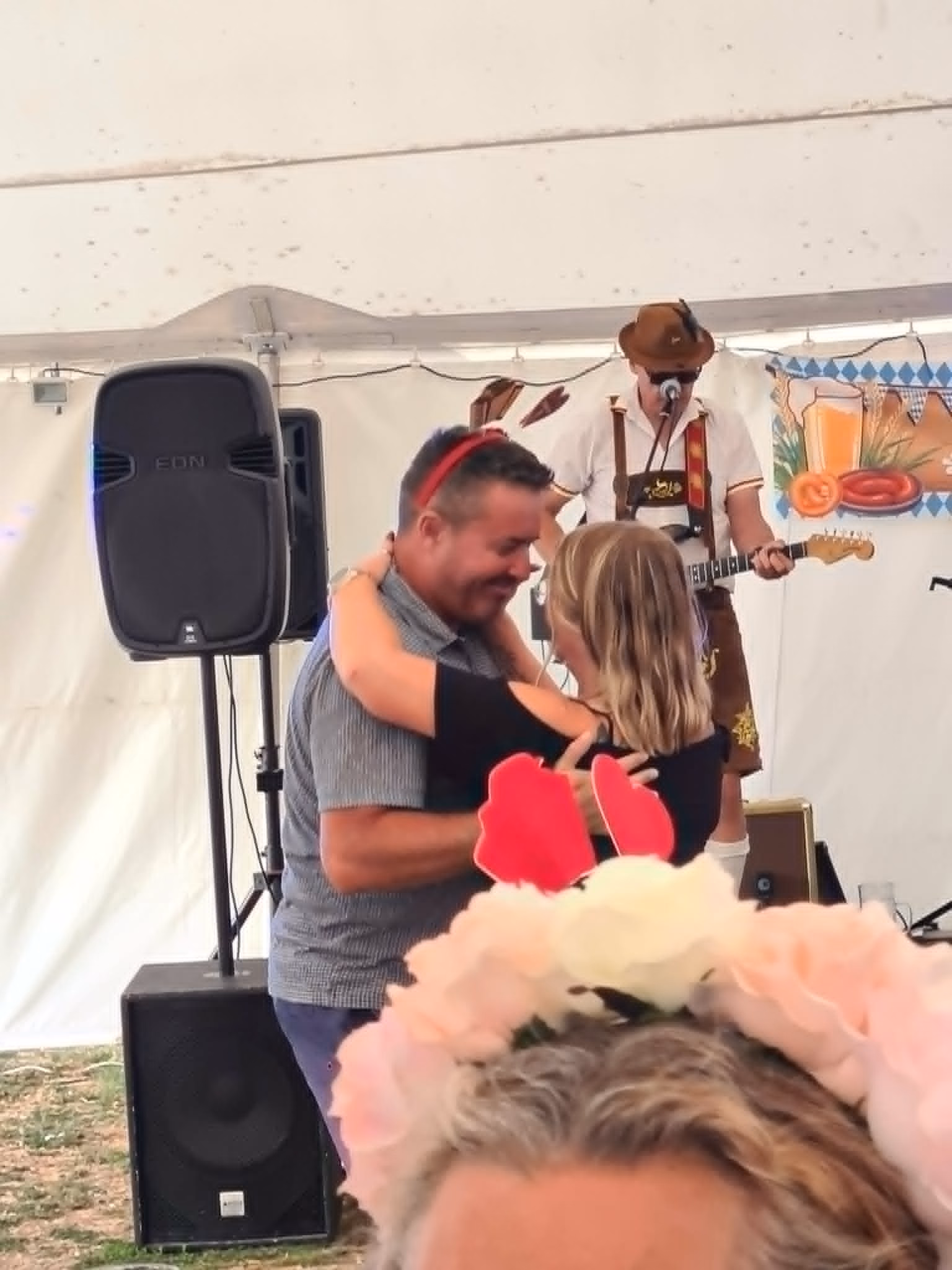 Two visitors dancing in the marquee while an Oompah musician performs on stage behind them.