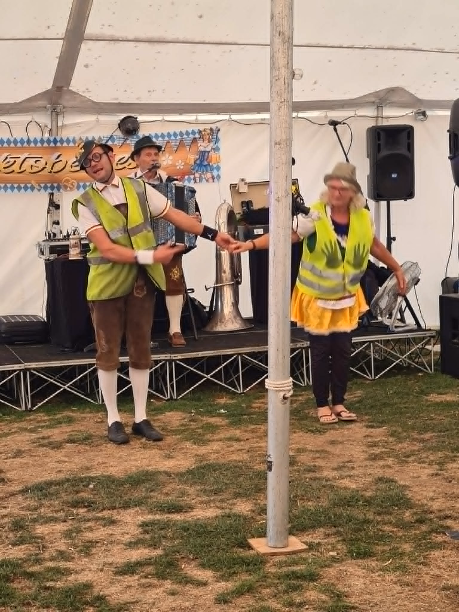 An Oompah performer in Bavarian dress leading a playful audience moment in front of the stage.