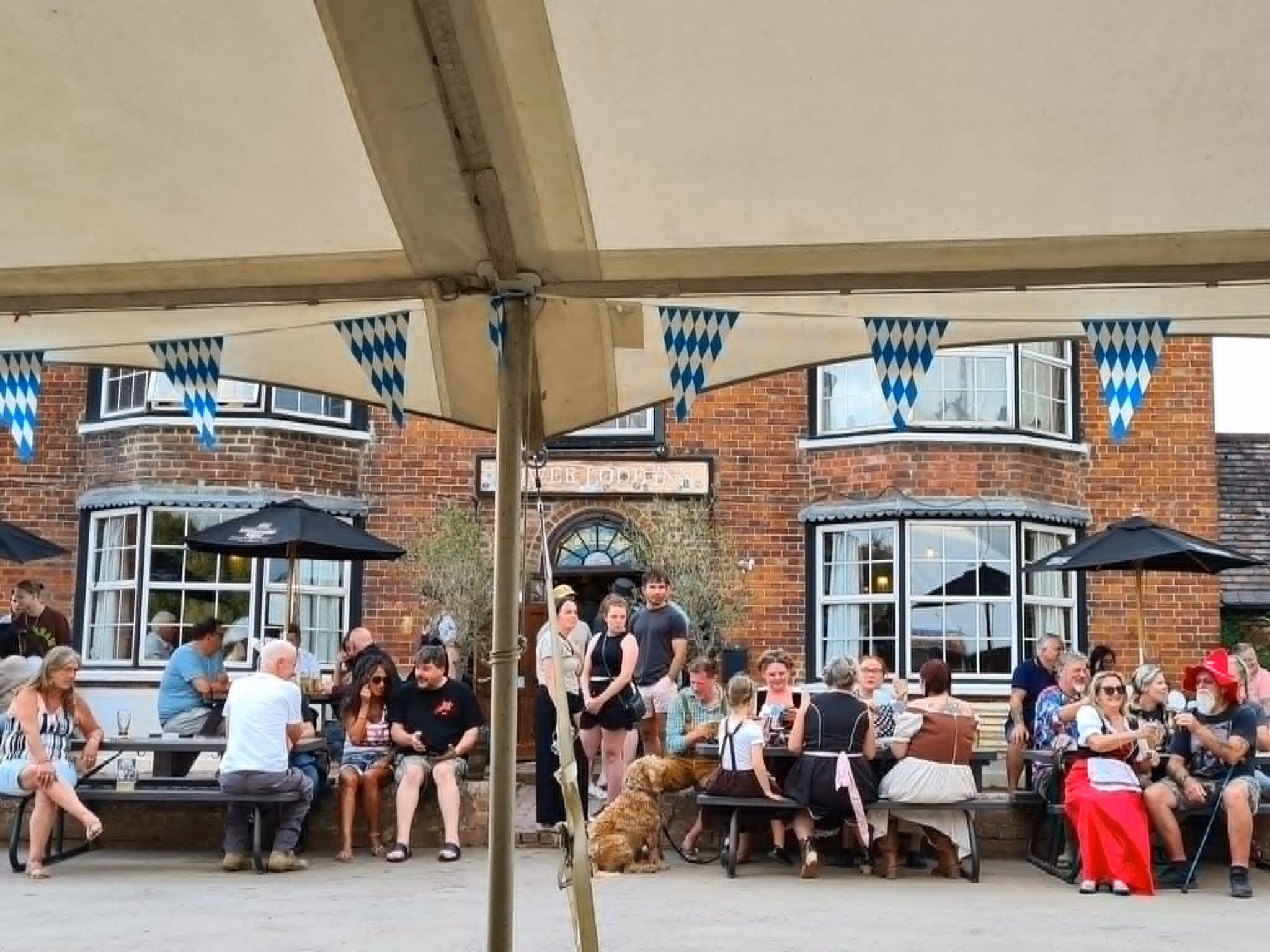Visitors gathering outside the Lower Lode Inn beneath blue-and-white Bavarian bunting before the 2025 festivities.